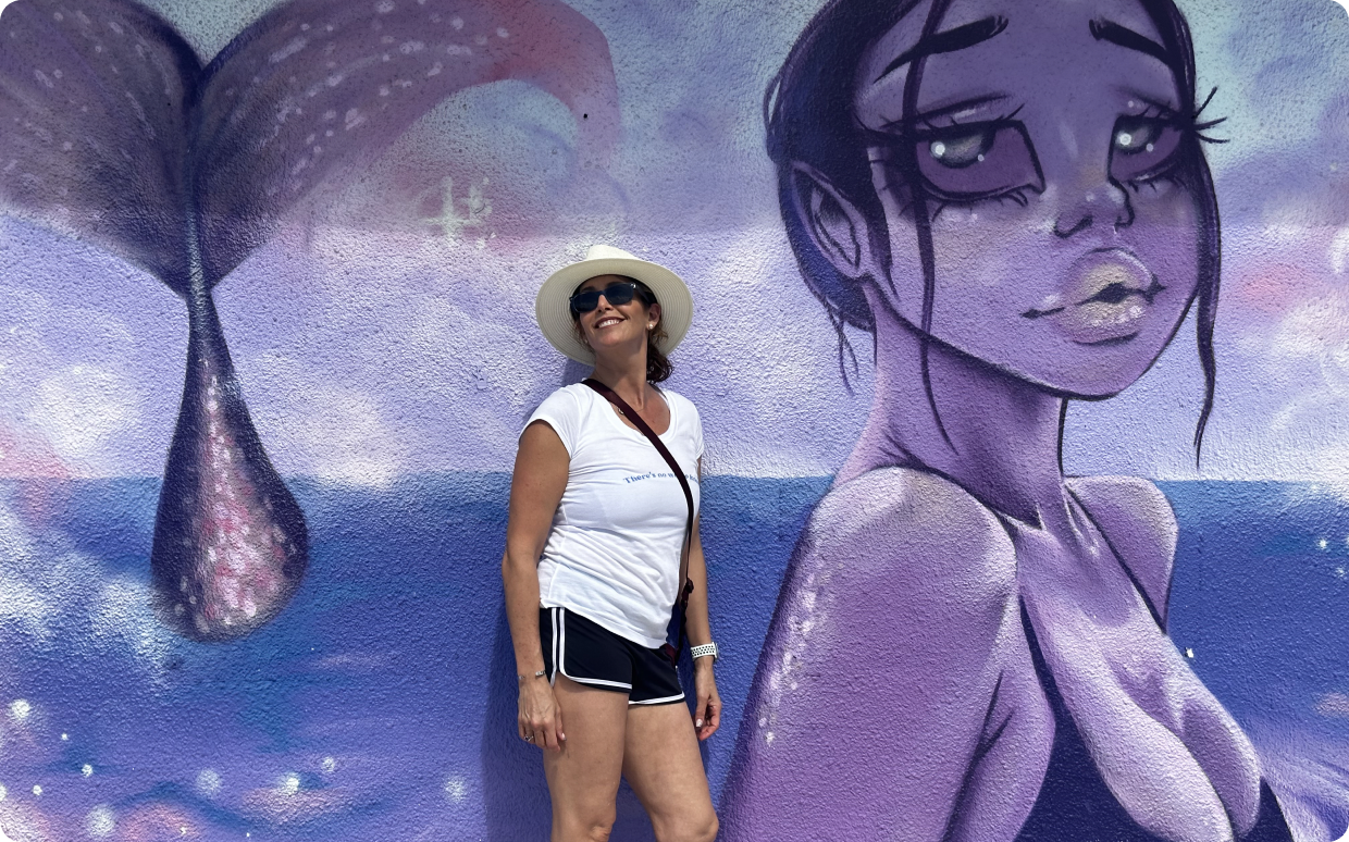 Smiling woman with whimsical mural backdrop