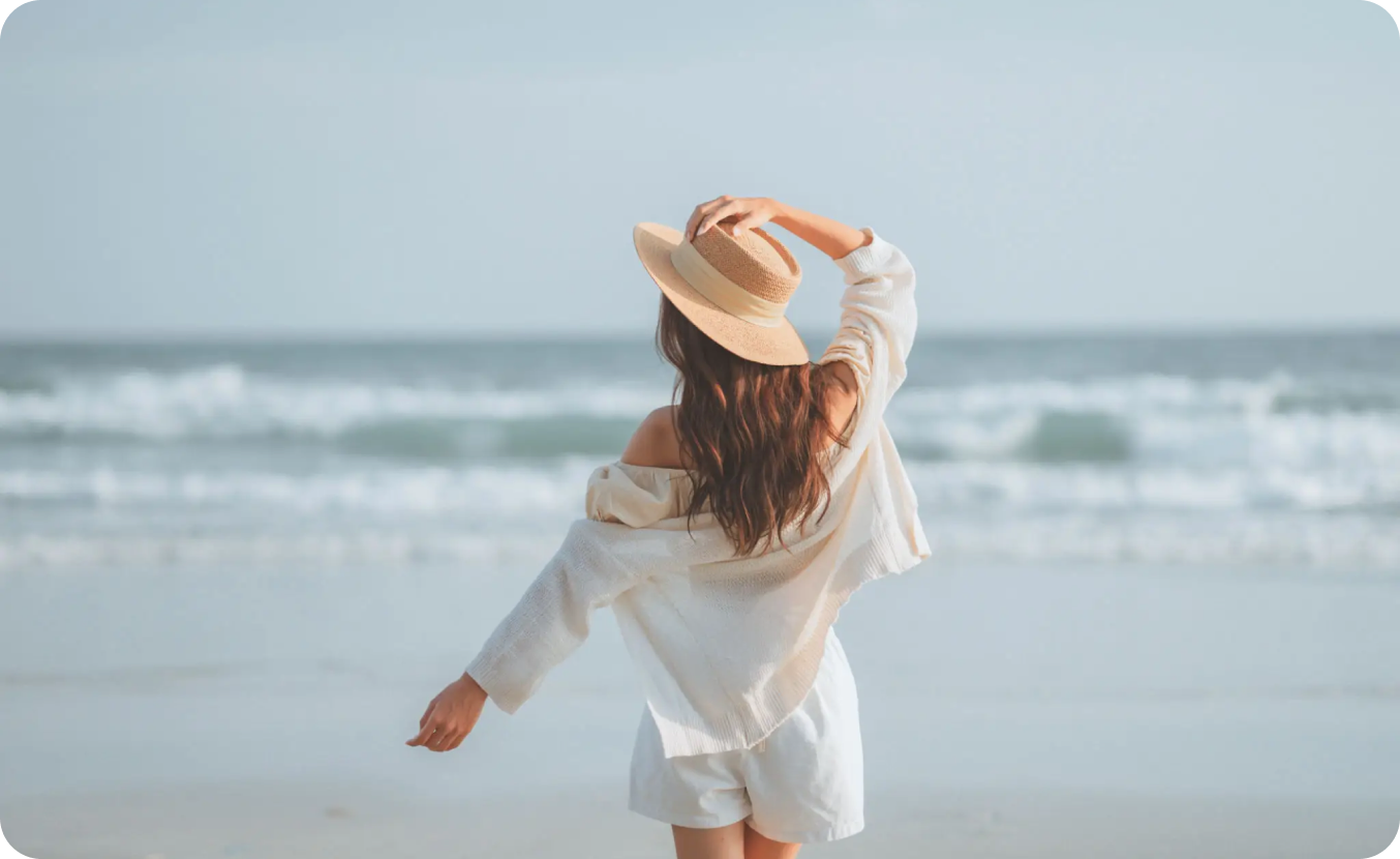 Stylish woman with hat facing the sea
