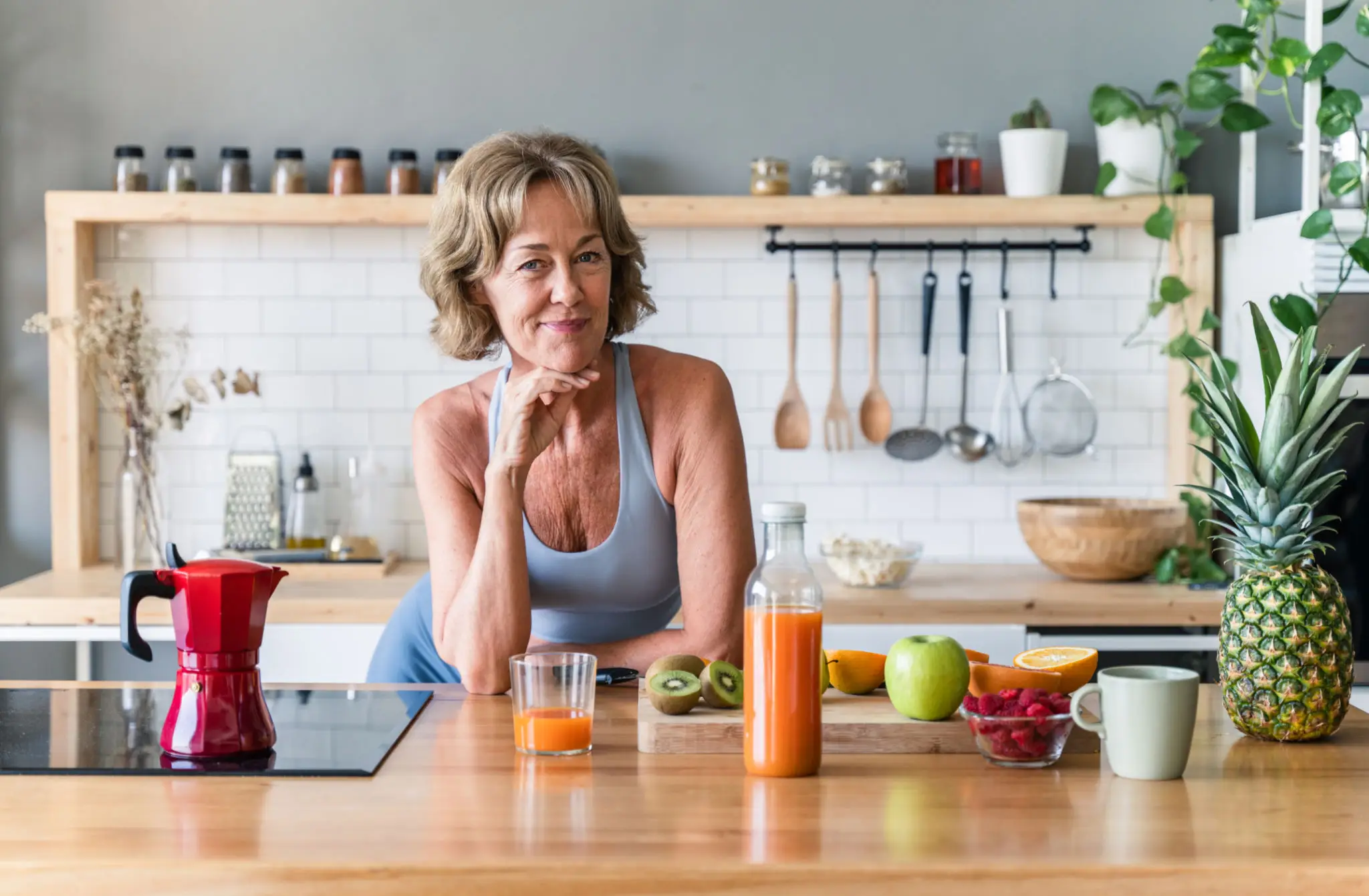 A woman standing in a kitchen with fresh juices and fruits.