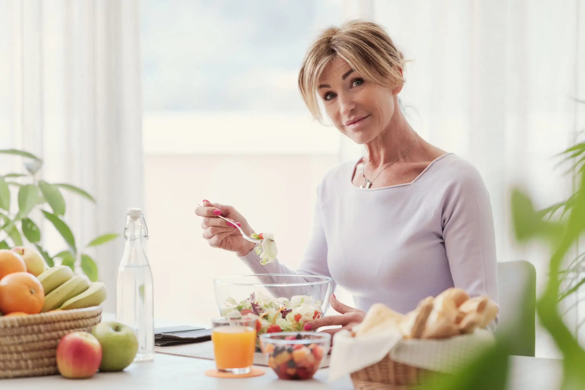 A woman enjoying a healthy breakfast with fruits and juice.