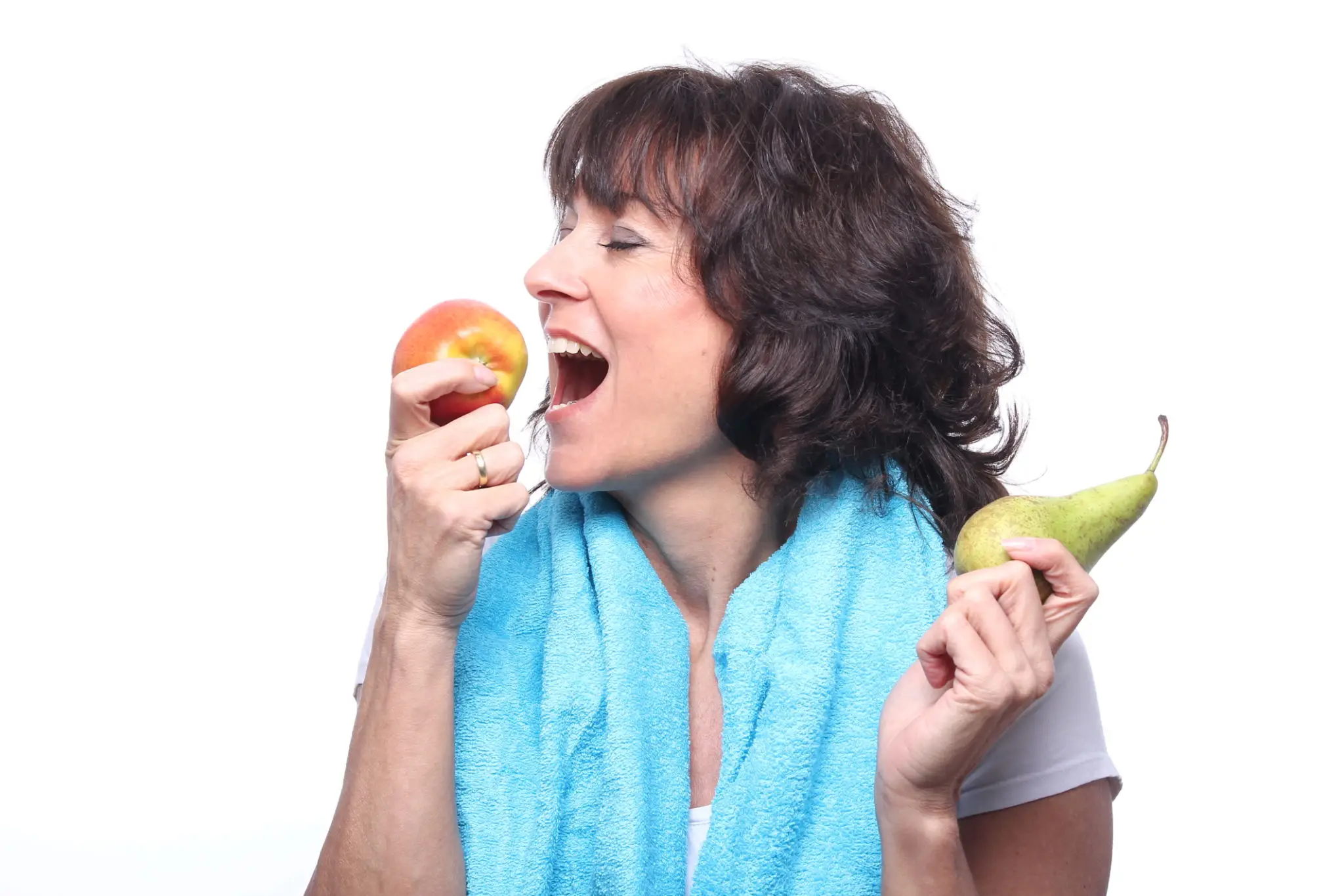 Woman choosing between an apple and a pear with a towel around her neck.
