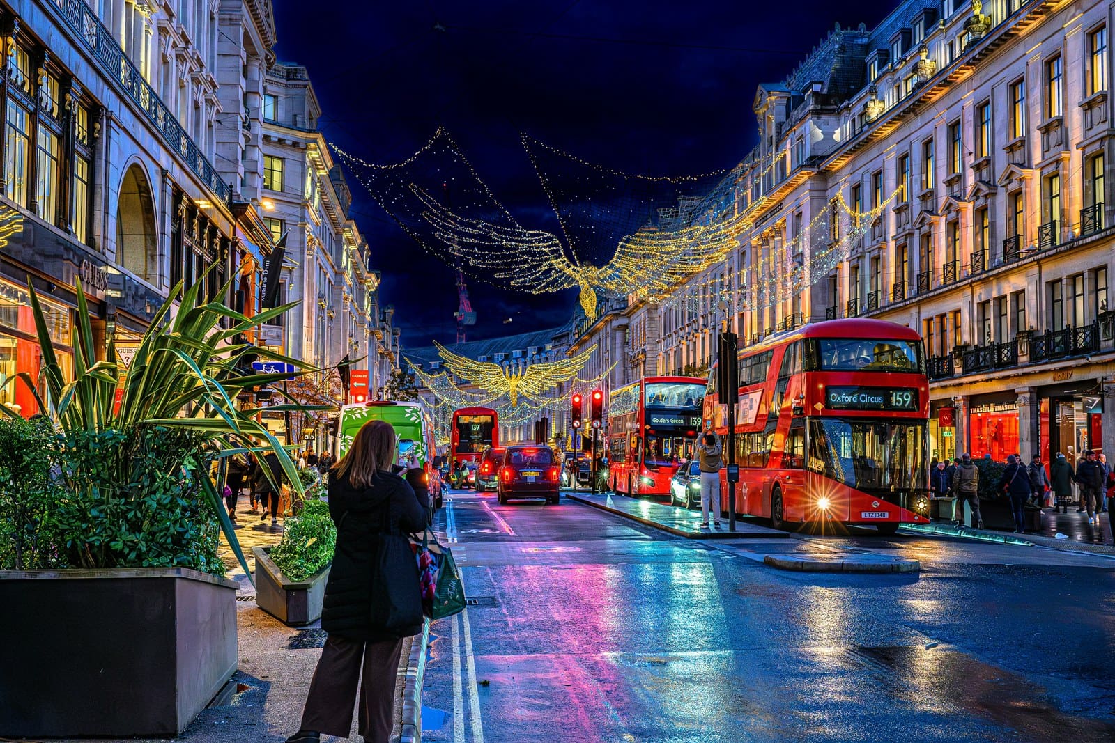 A European city street at dusk in winter, lights reflecting on wet pavement