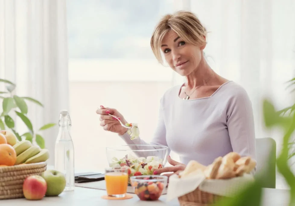 A woman enjoying a healthy breakfast with fruits and juice.