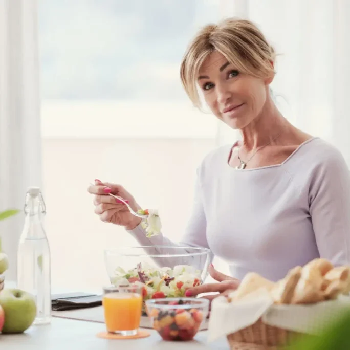 A woman enjoying a healthy breakfast with fruits and juice.
