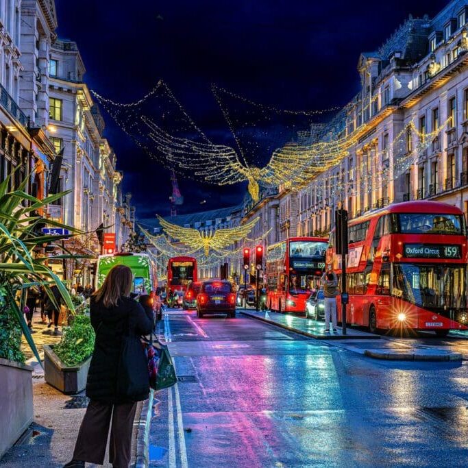A European city street at dusk in winter, lights reflecting on wet pavement